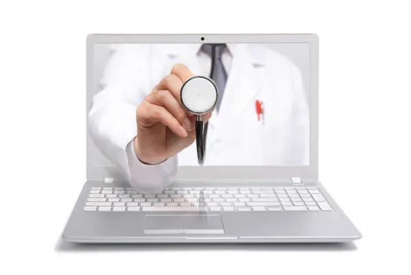 A person holding up a stethoscope in front of a laptop.