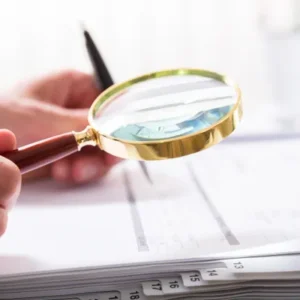 A person holding a pen and magnifying glass