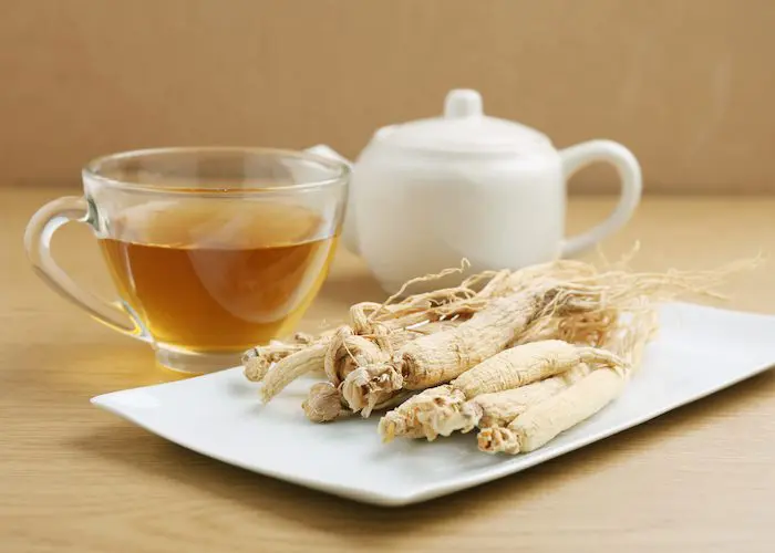 A white plate topped with some food and a cup of tea.